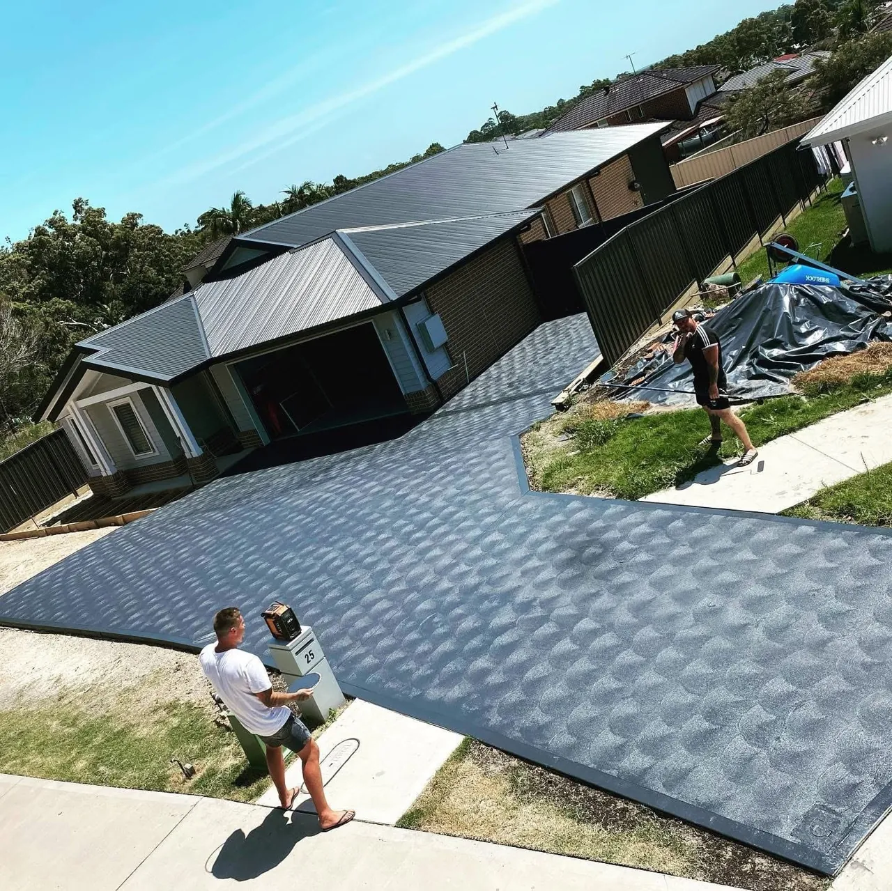 Concreting crew finishing a large residential driveway pour