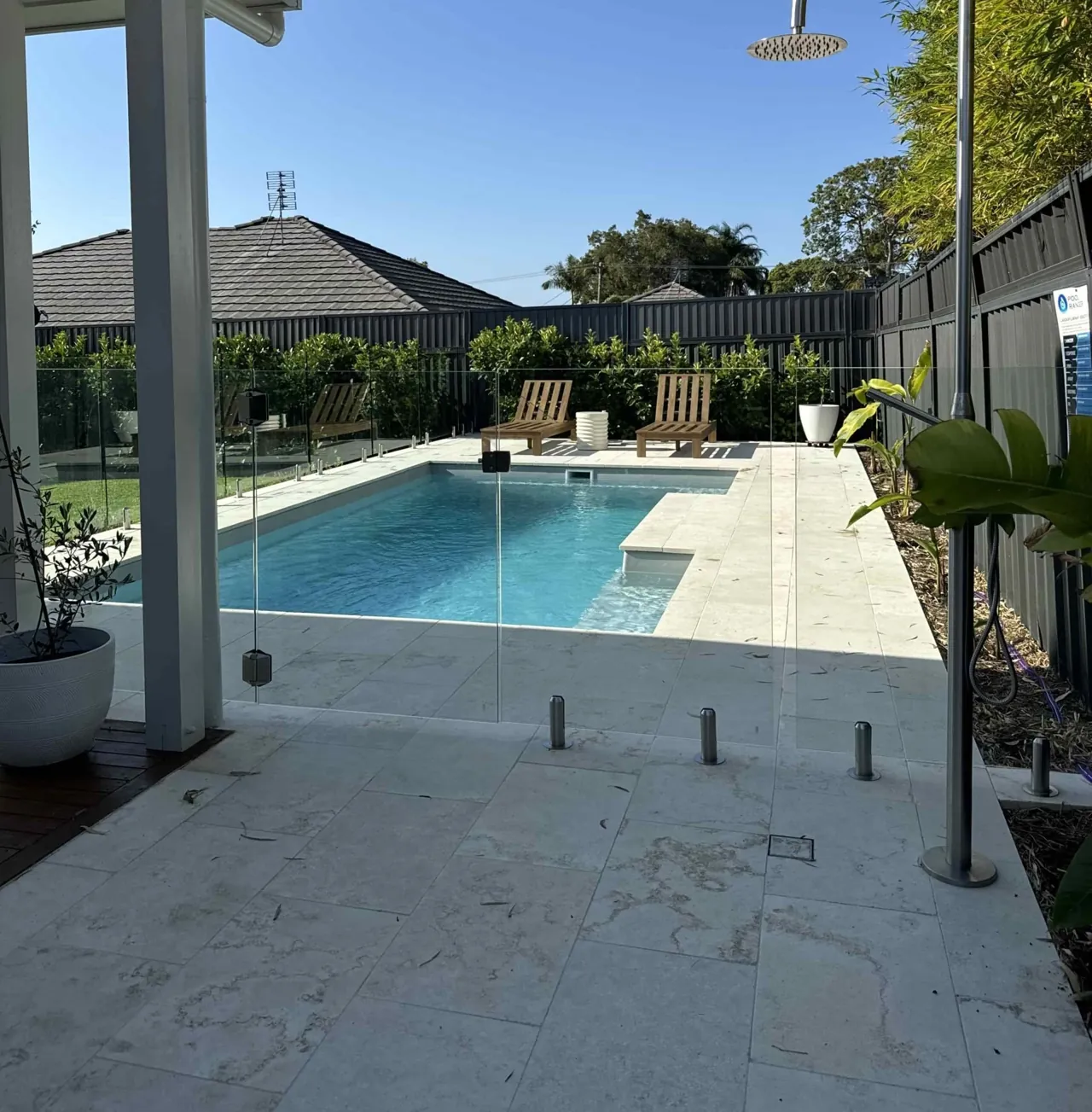 Concrete pool surround beside a rectangular backyard pool